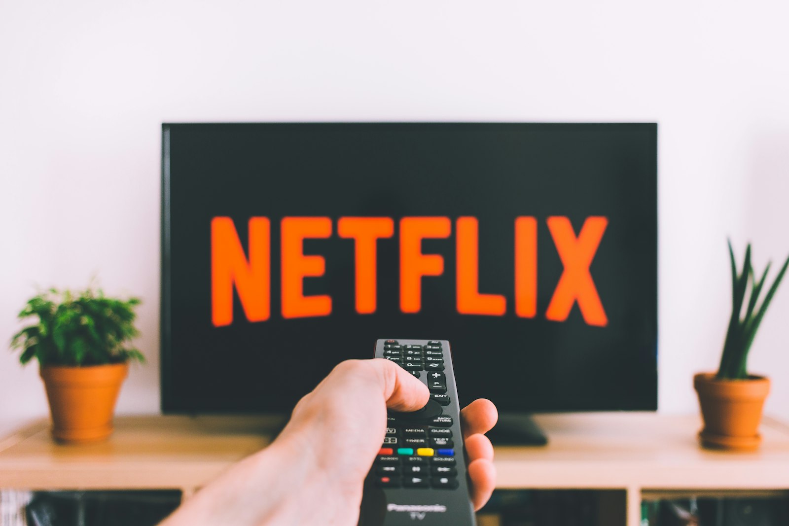 Main tenant une télécommande devant un téléviseur IPTV